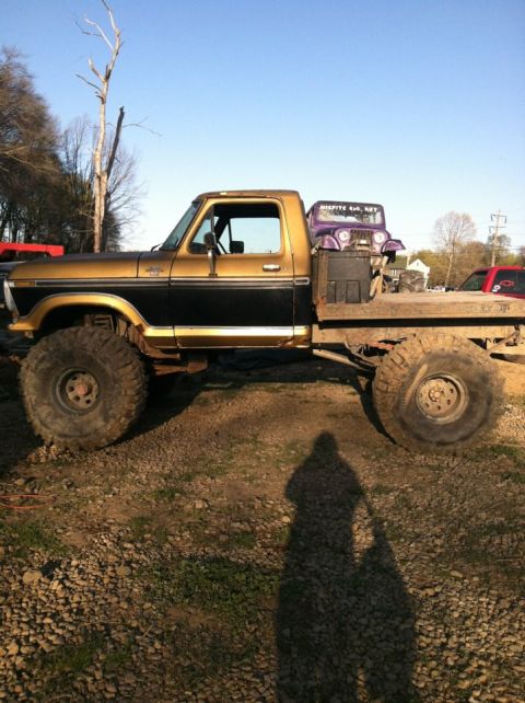 1990 Ford Bronco - This lifted flatbed truck, likely a 1979 Ford F-Series, is carrying a purple Jeep on its bed.