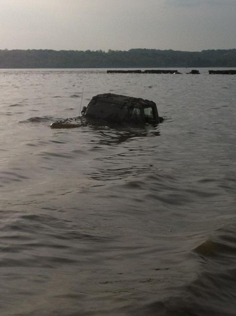 1990 Ford Bronco - A vehicle is submerged in water, with only its upper portion visible above the waves.