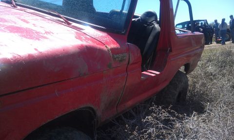 1978 Ford Bronco - 1978 Ford Bronco in a field, doors off. Another vehicle and group of people are in the background.
