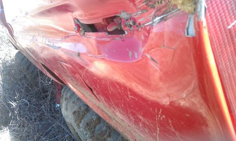 1978 Ford Bronco - The side of a red vehicle shows significant damage, including a large dent and visible pink fluid leakage.