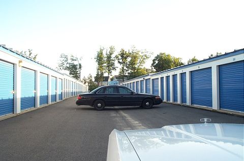 2001 Ford Crown Victoria - Side view of a black 2001 Ford Crown Victoria parked between rows of blue storage unit doors.