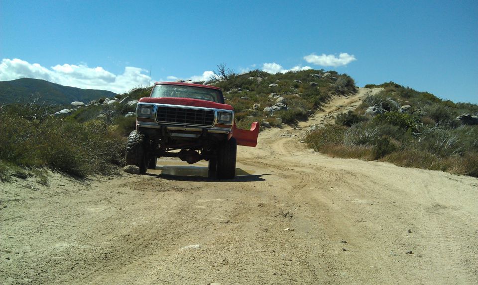 Red 1979 Ford F-Series truck with lifted suspension on a dirt trail