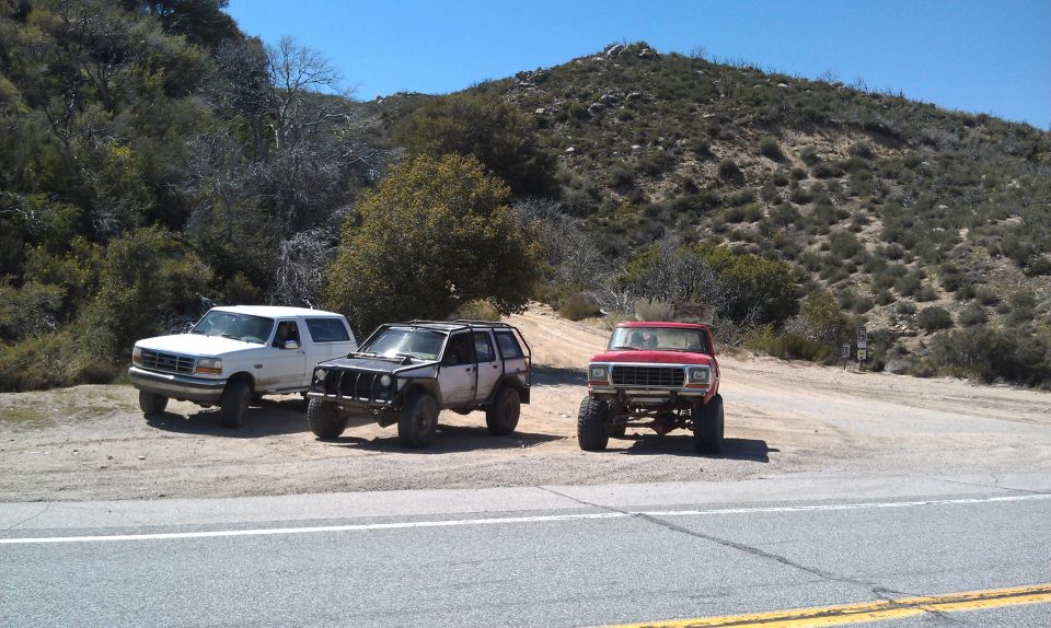Red 1978 Ford Bronco front view, lifted with off-road tires, parked on dirt