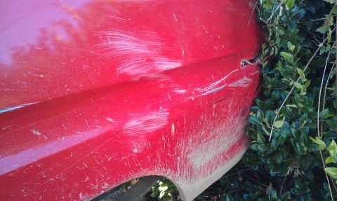 1978 Ford Bronco - A red vehicle's side shows extensive damage from off-road use, with mud and scratches covering the body panels.