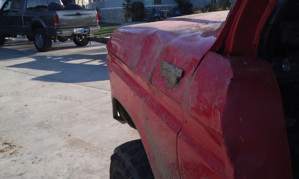 Red 1978 Ford Bronco fender with dent and visible badge