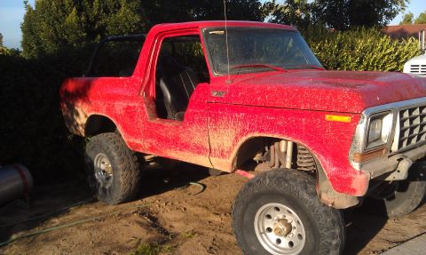 1978 Ford Bronco - This red SUV appears to be a Ford Bronco, but the specific year is not definitively identifiable from the image.