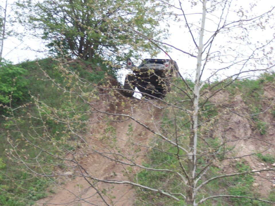Off-road vehicle climbing dirt embankment, 3q-front view