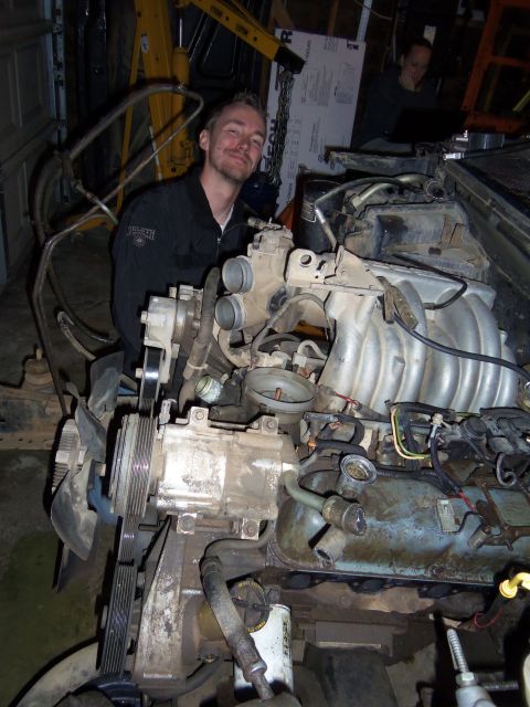 1968 Ford Bronco - A man poses near a disassembled engine, with a hoist visible in the garage.