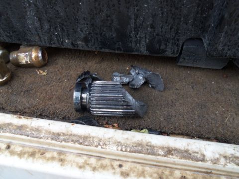 1989 Ford Bronco - A broken axle shaft lies on the ground next to some lug nuts.