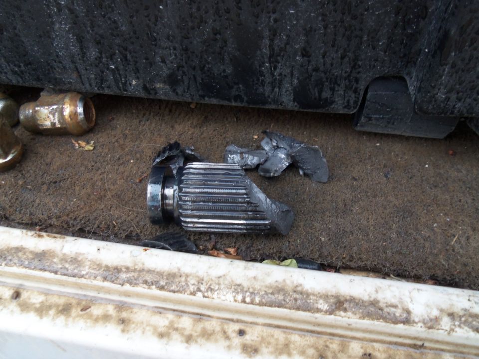 Broken axle shaft with splines and surrounding debris on dirty ground