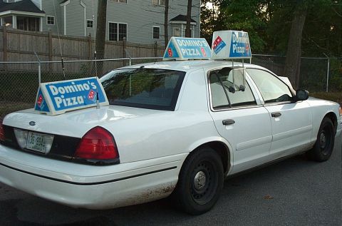 2001 Ford Crown Victoria - A white 2001 Ford Crown Victoria serves as a pizza delivery vehicle, adorned with Domino's Pizza signage.