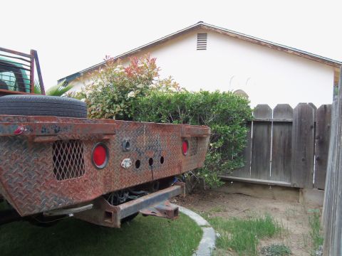 1968 Ford Bronco - The rear of a flatbed truck shows diamond plate metal, round taillights, and a trailer hitch.