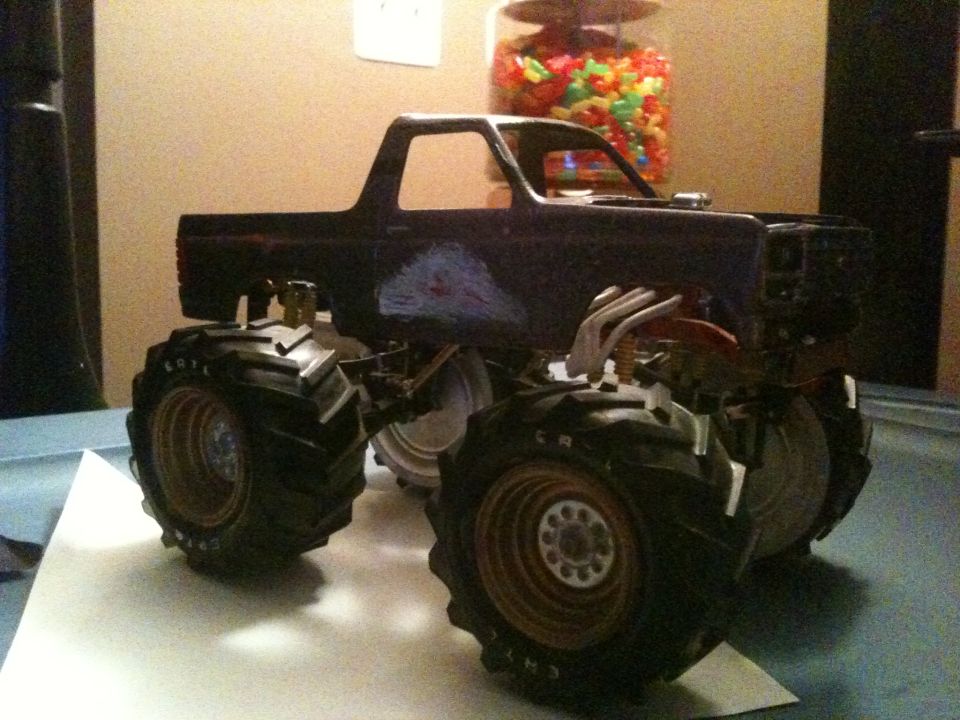 Dark scale model monster pickup on oversized lug tires, gold springs, chrome headers