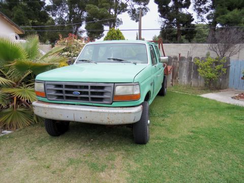 1968 Ford Bronco - This green Ford F-350 truck is parked on a grassy lawn in front of a wooden fence.