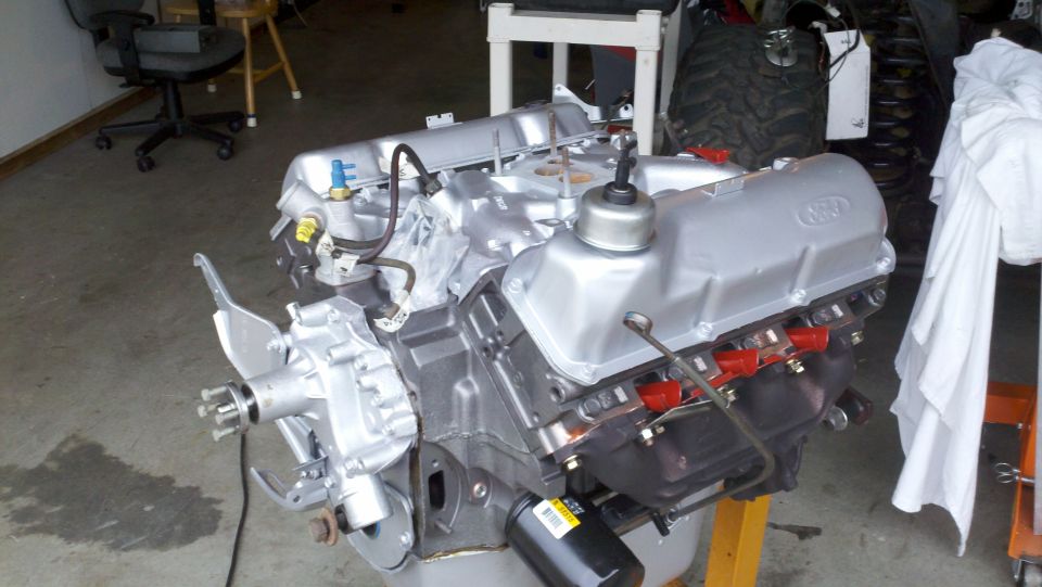 Ford V8 engine on stand, silver valve covers with 'FORD' embossed