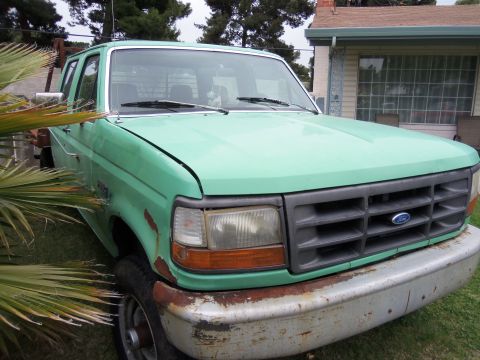 1968 Ford Bronco - This 1992 Ford F-350 pickup truck is green and shows signs of rust.