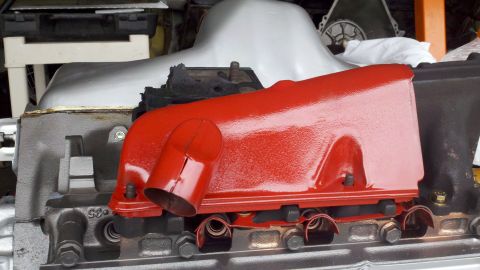 1978 Ford Bronco - Close-up of a red painted engine manifold, part of a motor rebuild.