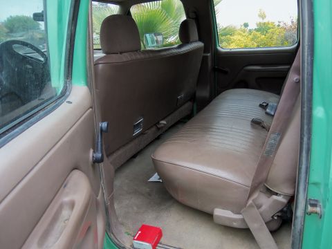 1968 Ford Bronco - The interior of a green truck, likely from the 1990s, with brown upholstery and a visible steering wheel.