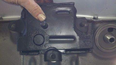 1978 Ford Bronco - Close-up of an engine oil filter housing being held by a hand, with part of the engine block visible.