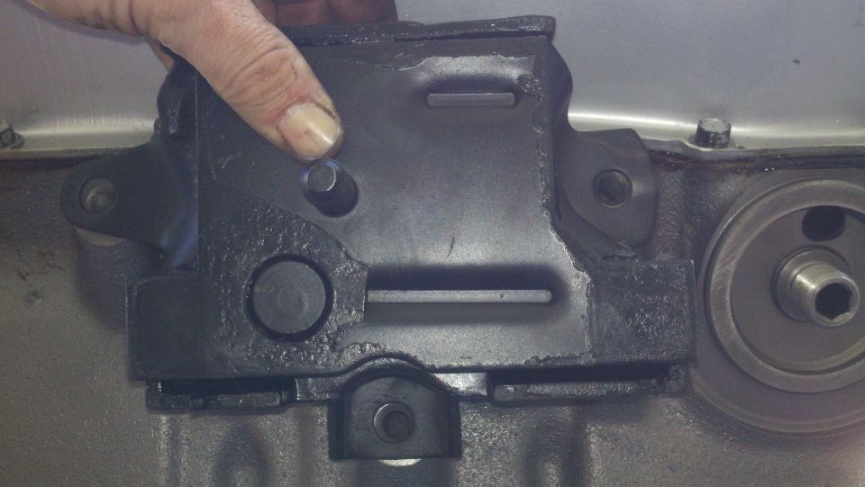 hand holding engine oil filter housing near engine block