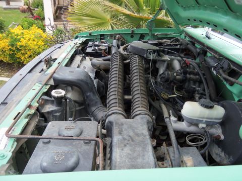 1968 Ford Bronco - Engine bay of a green truck, showing various components and hoses.
