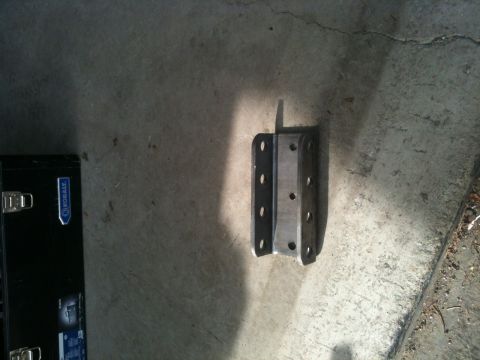 1990 Chevrolet Suburban - A metal bracket with numerous holes sits on a concrete surface next to a toolbox.
