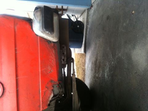 1990 Chevrolet Suburban - Close-up view of a red vehicle's fender and side mirror, showing some rust and wear.