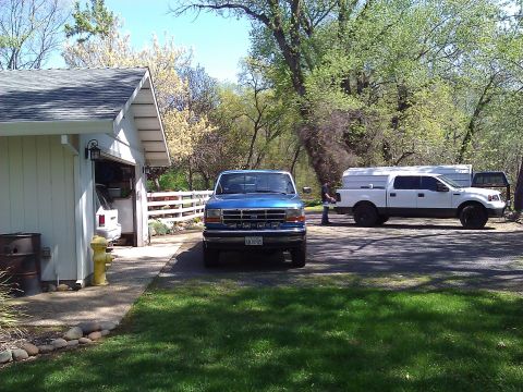 1992 Ford F-150 - A blue 1992 Ford F-150 is parked in front of a garage, with another white truck visible in the background.