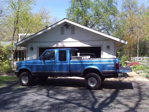 1992 Ford F-150 - This blue 1992 Ford F-150 crew cab pickup truck is seen parked in a driveway with a garage in the background.