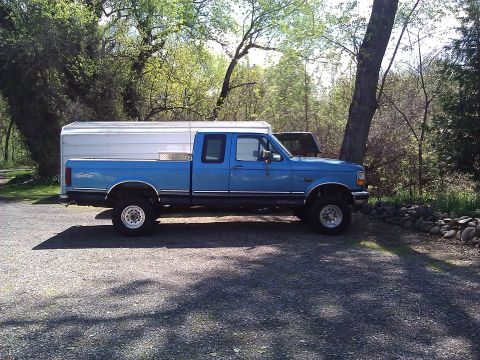 1992 Ford F-150 - Side view of a blue 1992 Ford F-150 pickup truck equipped with a white camper shell.