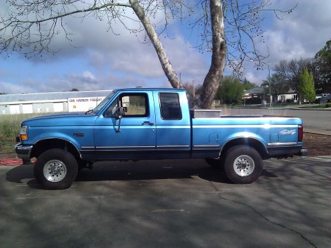 1992 Ford F-150 - This blue 1992 Ford F-150 pickup truck is shown from the side, a long bed and crew cab configuration.