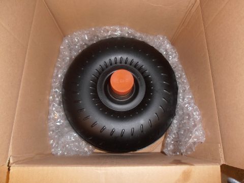 1990 Ford Bronco - A black torque converter with an orange cap is shown inside a cardboard box, protected by bubble wrap.