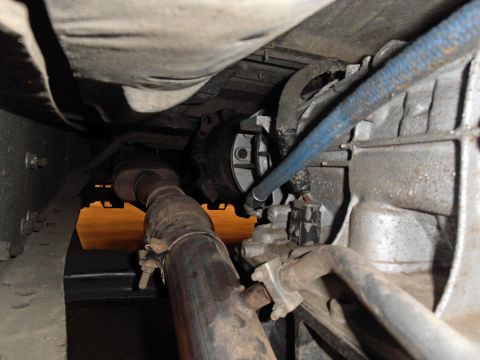 1990 Ford Bronco - Close-up view of the exhaust system and transmission components from underneath a vehicle.