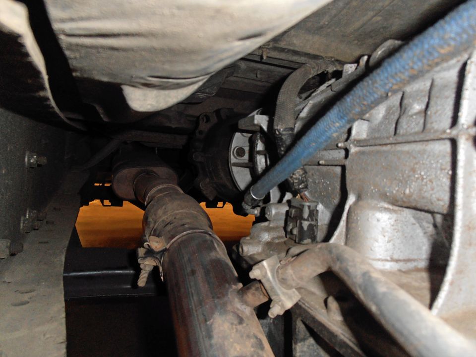 Underbody view of exhaust pipe and transmission housing with blue hose