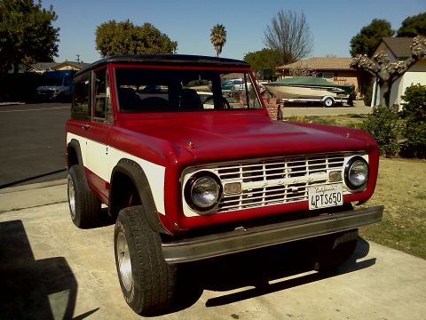 1968 Ford Bronco - A red and white 1968 Ford Bronco is parked in a driveway on a sunny day.