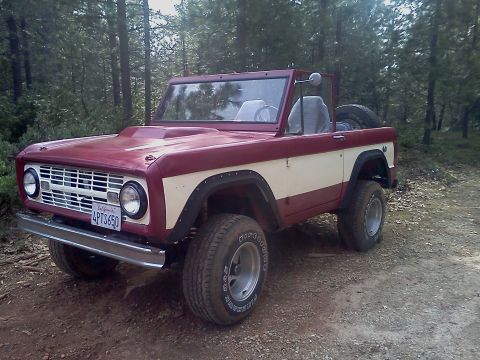 1968 Ford Bronco - This 1968 Ford Bronco is parked on a dirt road surrounded by trees. It has a two-tone paint scheme and off-road tires.