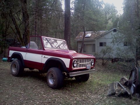 1968 Ford Bronco - A two-tone 1968 Ford Bronco sits in front of a cabin in a wooded setting.