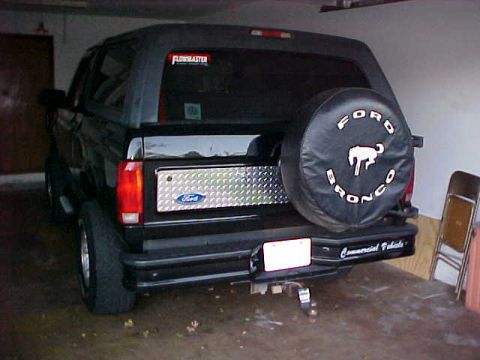 1995 Ford Bronco - The rear of a black Ford Bronco is parked indoors, showing its spare tire cover and tailgate details.