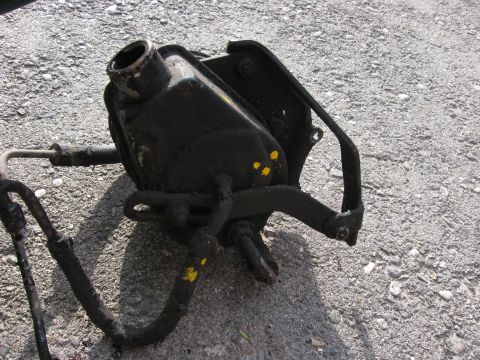 1981 Ford Bronco - A greasy power steering pump sits on a gravel surface, disconnected from a vehicle.