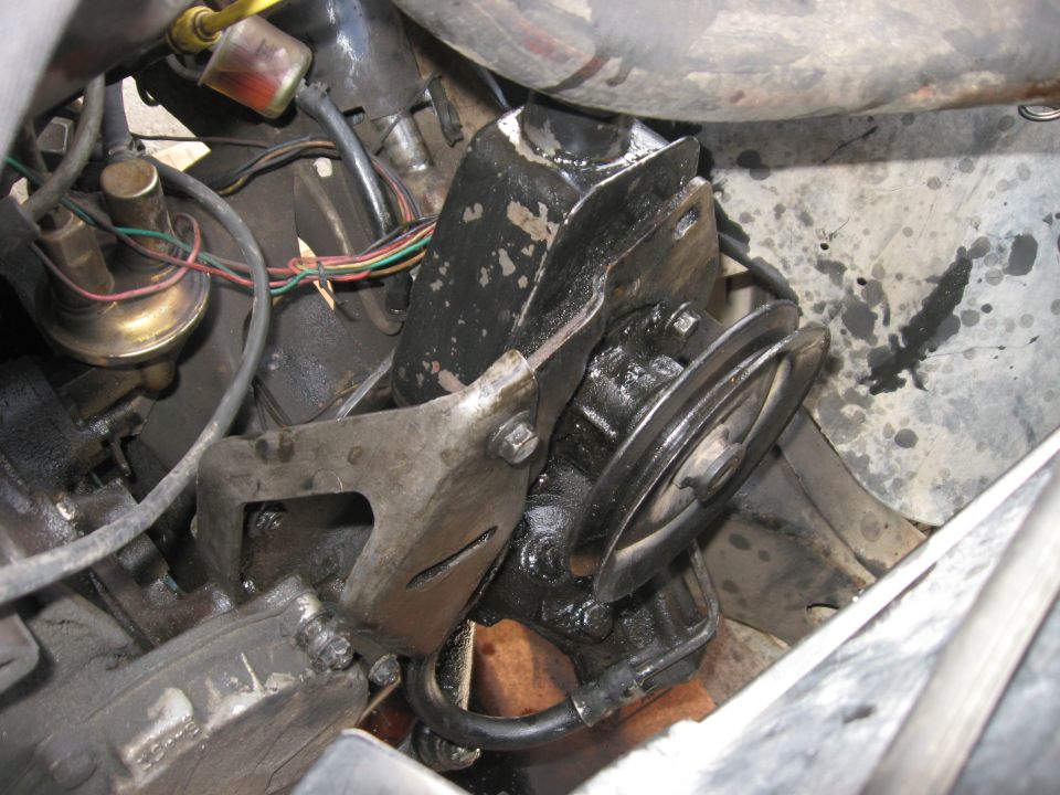 Black power steering pump with pulley and hoses, covered in grease