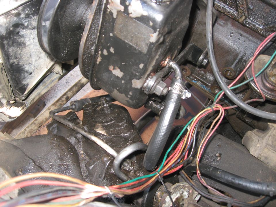 Close-up of engine bay parts with wires and hoses connected to a black component