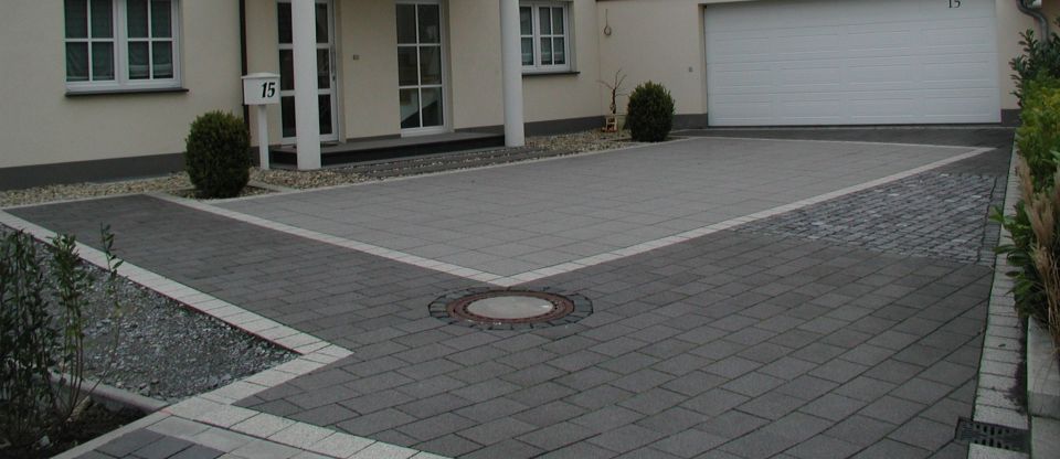 Driveway leading to a garage door, with a house and mailbox visible. There's a manhole cover in the driveway