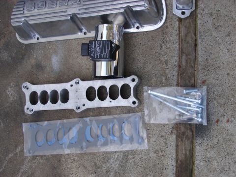 1973 Ford Ranchero - Engine parts including valve covers, intake manifold, and throttle body are displayed on a concrete surface.