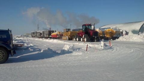 2009 Kenworth T800 - A red tracked tractor operates in a snowy environment alongside other heavy machinery and industrial buildings.