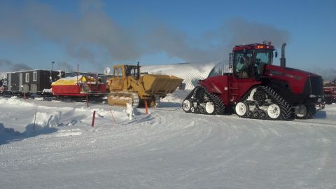 2009 Kenworth T800 - Two heavy machinery vehicles, a red tractor and a yellow bulldozer, are parked in a snow-covered landscape.