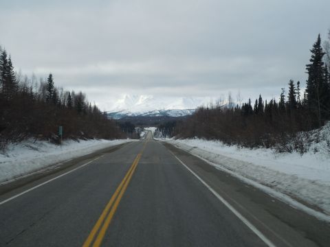 2009 Kenworth T800 - A desolate highway winds through a snowy landscape towards distant, snow-capped mountains.
