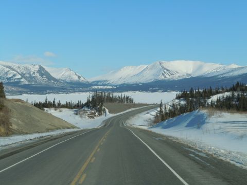 2009 Kenworth T800 - A road winds through a snow-covered valley with mountains in the background.