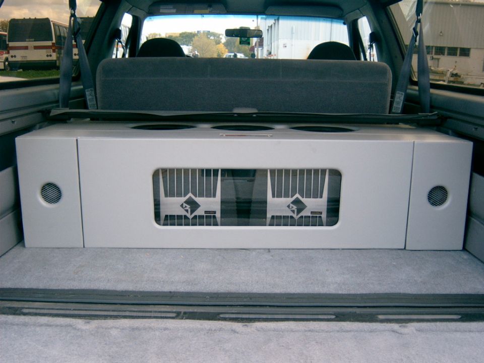 Carpeted rear cargo area subwoofer enclosure box behind folded SUV seat