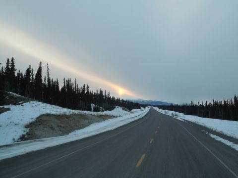 2009 Kenworth T800 - A desolate highway cuts through a snow-covered forest under a sky with sun dogs.