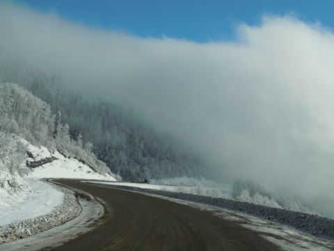 2009 Kenworth T800 - A road winds through a snow-covered mountain landscape partially obscured by fog.